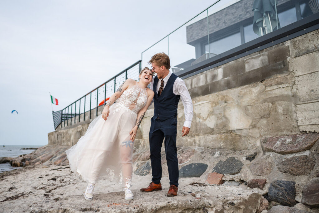 Braut und Bruder lachen am Strandabschnitt des Casa al Mare