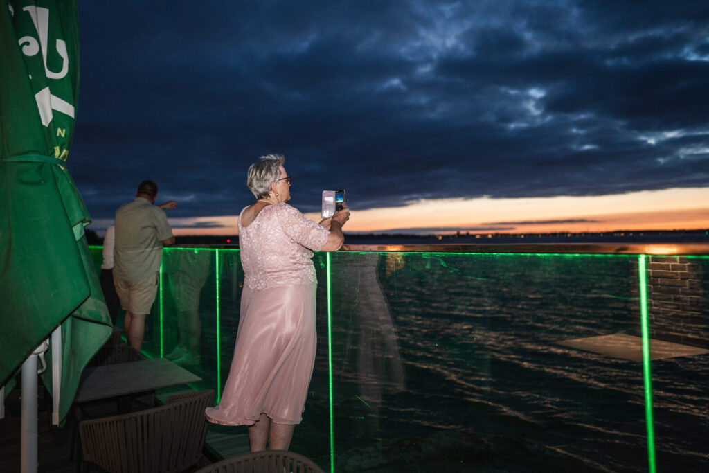 Frau fotografiert Sonnenuntergang über der Kieler Förde